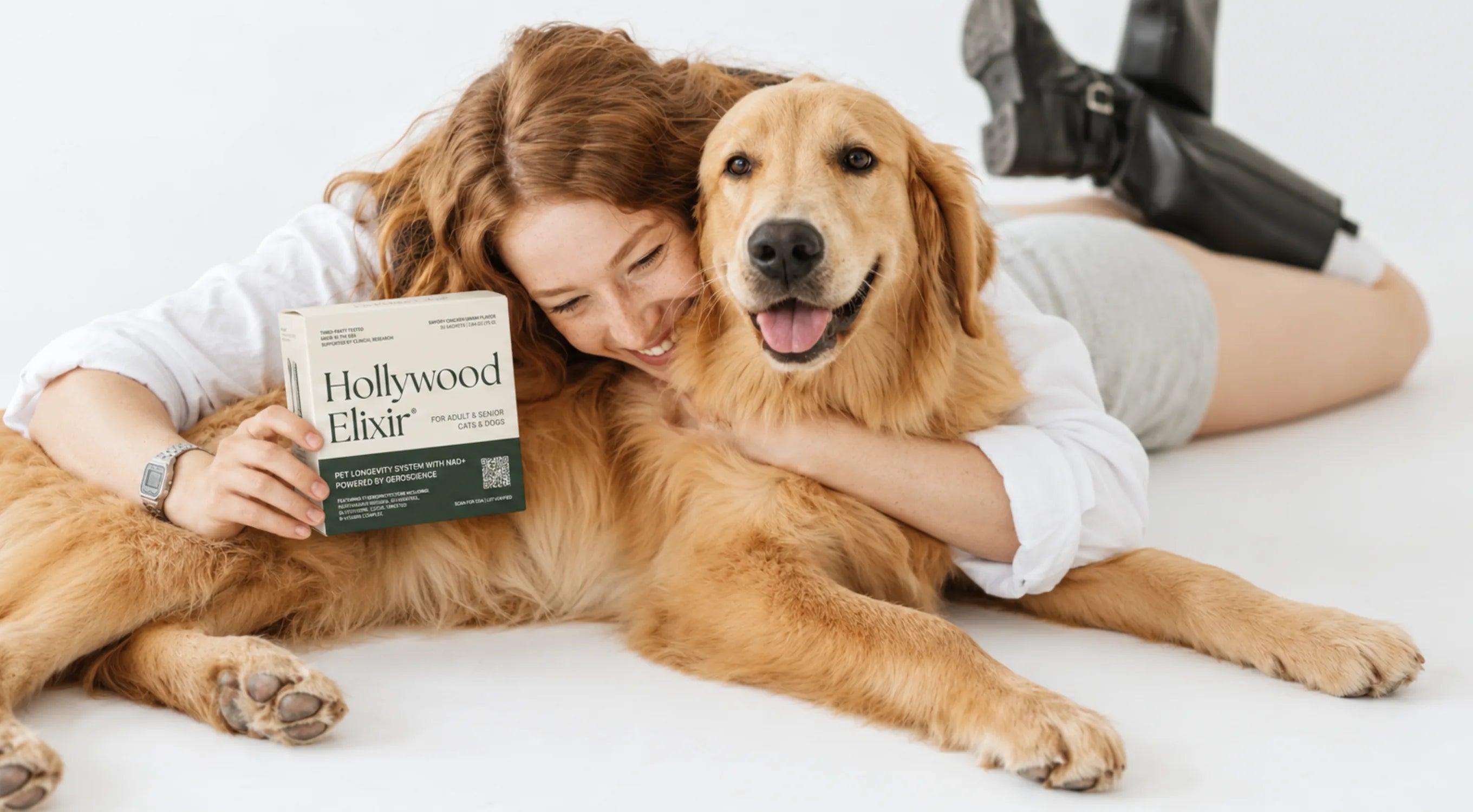 A woman hugging her golden retriever while holding a box of Hollywood Elixir