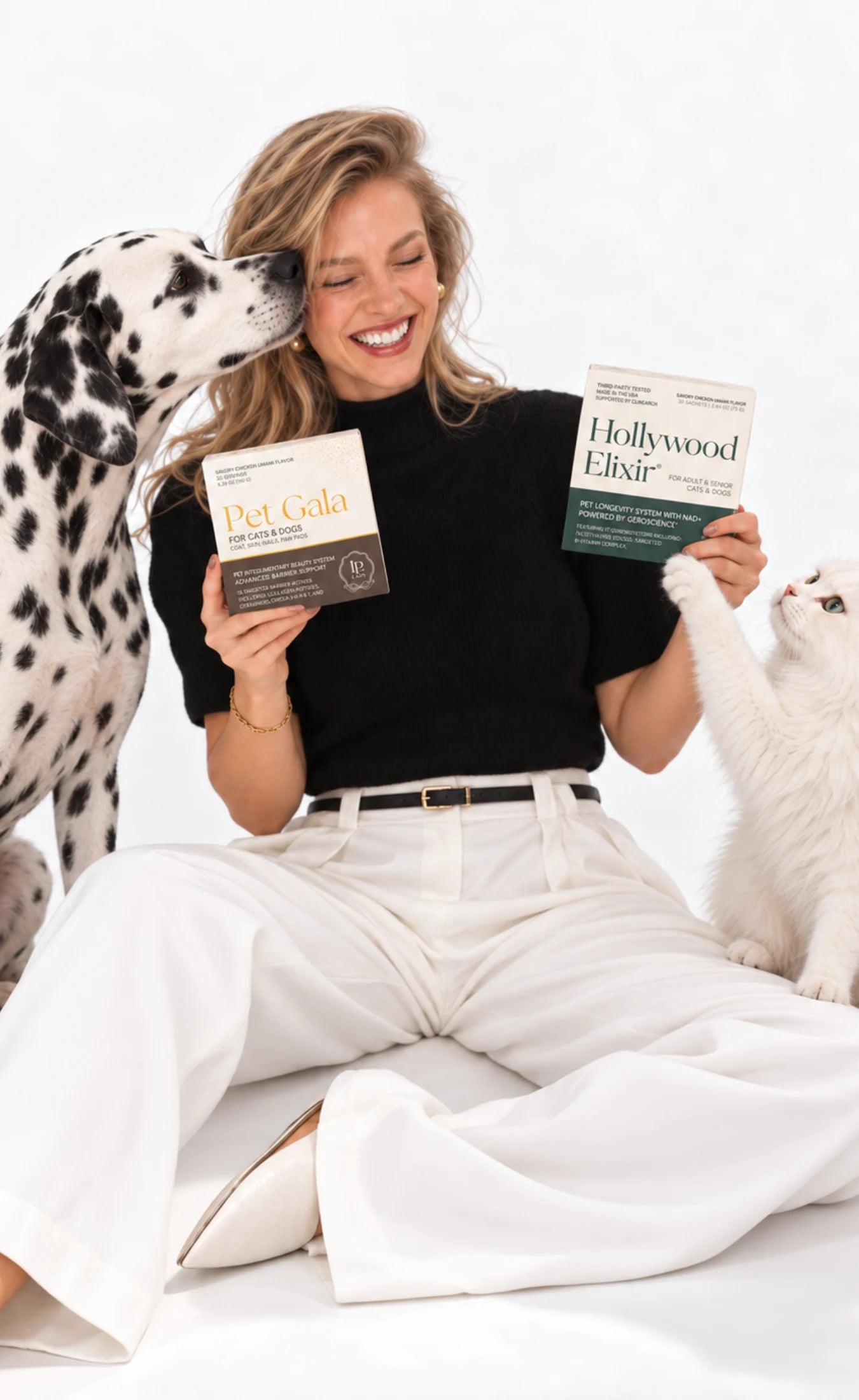 A woman with a Dalmatian and white cat holding Hollywood Elixir and Pet Gala